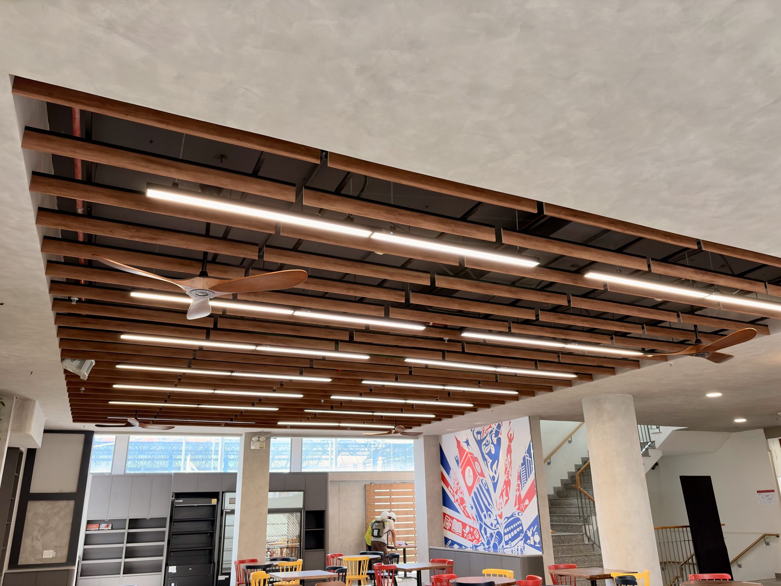 Trần tiêu âm PET dạng treo baffle vân gỗ ở khu bistro